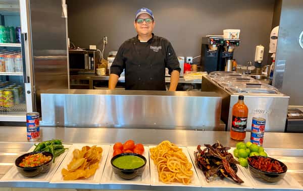 Casa de Cobre chef behind the counter with fresh salsas, chilies and toppings
